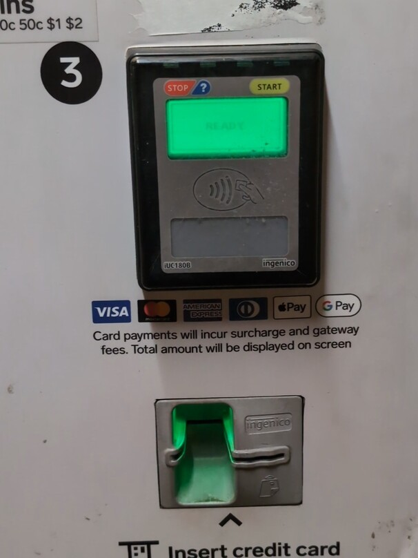contactless payment terminal on a parking ticket machine, with a very faded black on green monochrome lcd. it reads “READY”