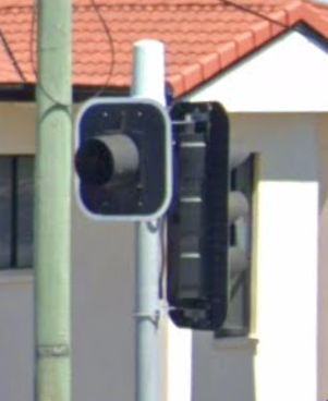 two collared sets of traffic lights, one facing away with three aspects, and one facing towards with only one aspect