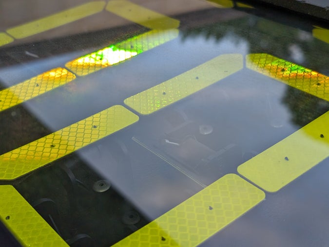 closeup of a seven-segment display that reads 000, with its lime-green retroreflective surface glowing iridescent