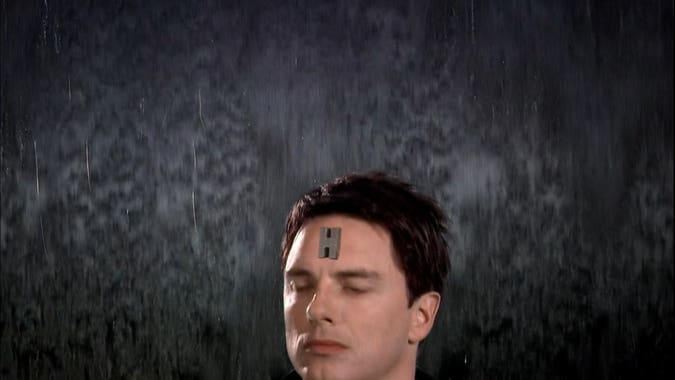 jack harkness with an “H” symbol on his forehead, indicating that he is a hologram, rising from the bottom of the frame