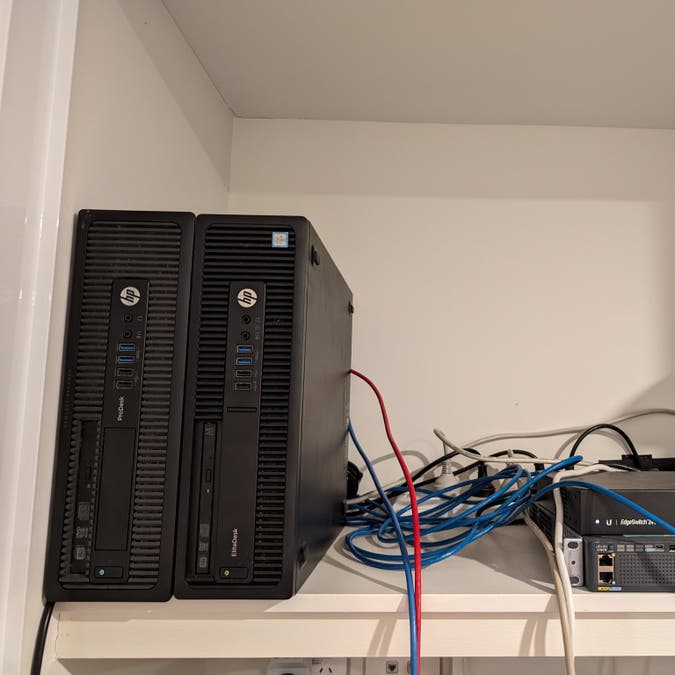 two hp sff computers on a shelf, next to some ethernet switches